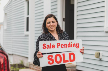Realtor holding a ‘sale pending’ and ‘sold’ sign